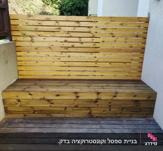גדר עץ עם ספסל עץ בגינה